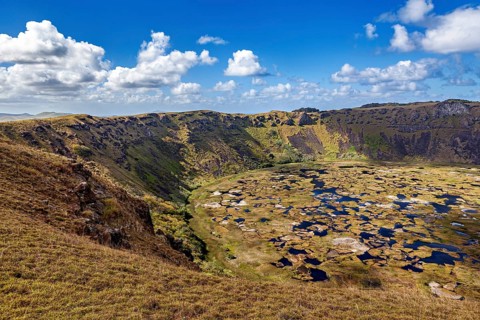 A distinctive crater with rocks and lush vegetation nestled in a volcanic landscape, the Ranu Kau