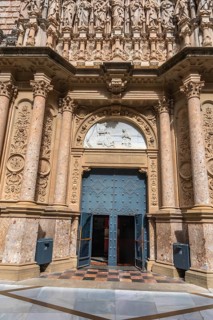 Open entrance of the montserrat monastery, revealing intricate sculptures, ornate architectural