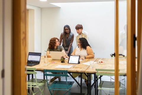A diverse group of colleagues engaging in a coworking space, discussing ideas with laptops and