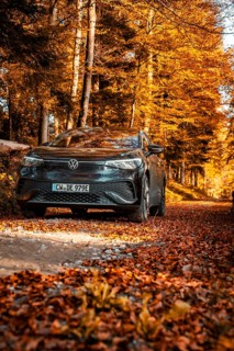 Car in autumn forest with orange leaves on the road, electric car VW ID5, Gechingen, Black Forest,