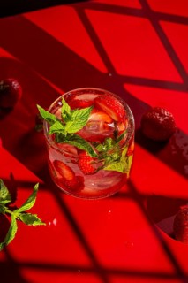 From above refreshing strawberry mojito cocktail garnished with mint, set against a vivid red