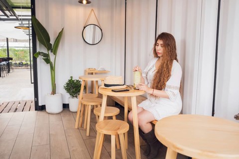 A young American Latin woman with long hair enjoys a refreshing drink at a cozy cafe. Surrounded by
