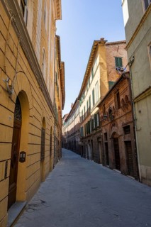 View of a small street going through old buildings in the city of Siena, Tuscany, Italy