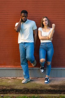 Vertical full length photo of a multi-ethnic models with denim clothes standing leaning on urban