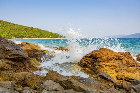 Wellen brechen an einem Felsen im Meer an einem sonnigen Tag auf der Insel Cres, Kroatien