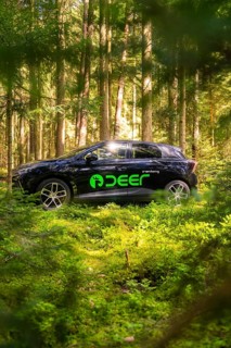 Black vehicle parked in a wooded area, surrounded by sunlight, Deer E- Carsharing, Calw, Black