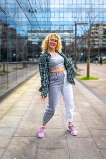 Caucasian woman with blond curly hair dancing in urban style in a city street wearing casual