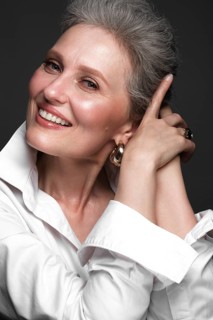 Portrait of a beautiful elderly woman in a white shirt with classic makeup and gray hair