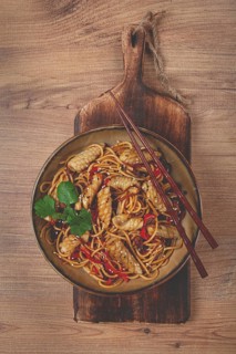 Udon noodles, with squid and vegetables, on a wooden table, homemade, no people
