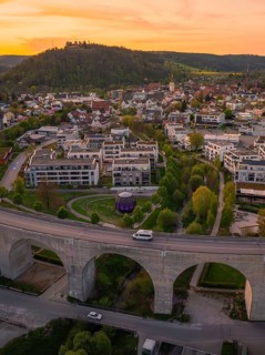Urban view with viaduct and small houses in a hilly landscape at sunset, Nagold, district of Calw,
