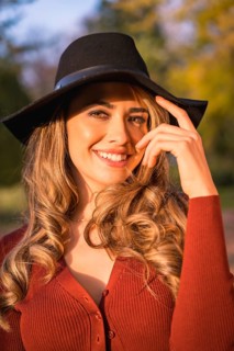 Lifestyle, portrait of a caucasian girl in a black hat at sunset in a green park