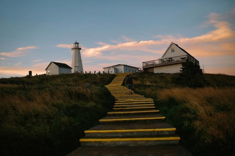 Back view of an unrecognizable man ascending a yellow painted staircase towards the historic Cape