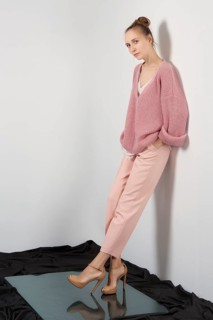 Pretty girl in thin angora sweater and slim pants posing near the wall