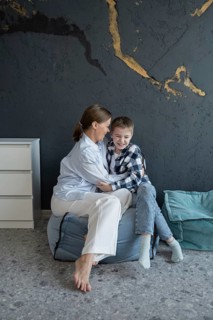 A mother and her son share a warm embrace while sitting on a comfortable bean bag in a stylish