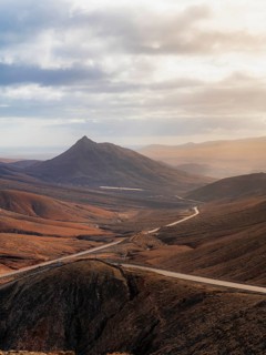 A breathtaking view of a winding road cutting through the rugged mountains of Fuerteventura. The