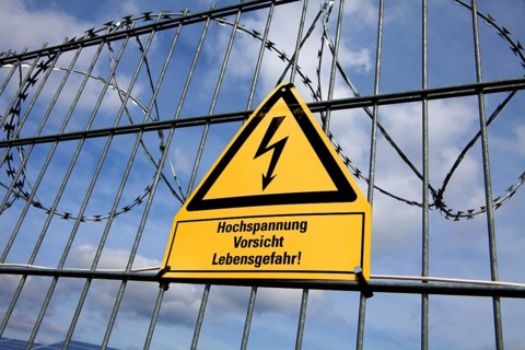 Signpost and fence at an open space solar photovoltaic plant, Germany