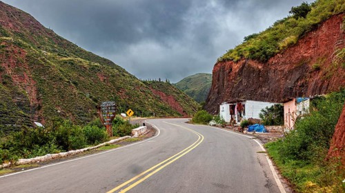 Empty street with houses in a mountainous, cloudy landscape, roads through the countryside of