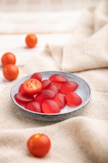 Jelly tomato candies on white wooden background and linen textile. close up, side view, selective