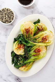 Grilled bok choy served with soy sauce and sesame seeds, on a white plate, homemade, no people