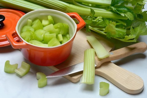 Celery stalks, pieces in pots with kitchen knife