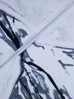 Aerial view of a pristine winter landscape in Iceland, captured by drone. A solitary road cuts
