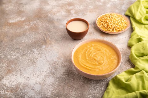 Pea cream soup, Puree, porridge in ceramic bowl on brown concrete background and green linen
