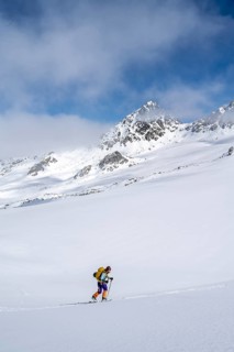 Ski tourer ascending through a picturesque snow-covered mountain landscape with views of mountain