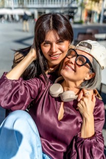 Two smiling women, a mother and her adult daughter, embracing and enjoying a moment of family