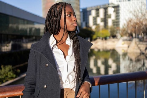 African American businesswoman with braids, dressed in a professional blazer and shirt, enjoying a