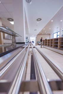 Modern food delivery in a canteen with stainless steel surfaces and floor tiles, surrounded by an