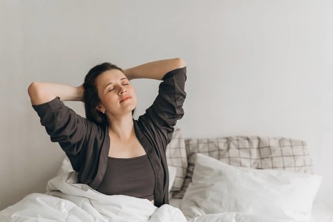 A serene morning moment with a woman relaxing in bed, embodying wellness and self-care. This image