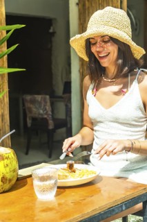 Young woman wearing straw hat enjoying a meal at an outdoor restaurant in siargao island,