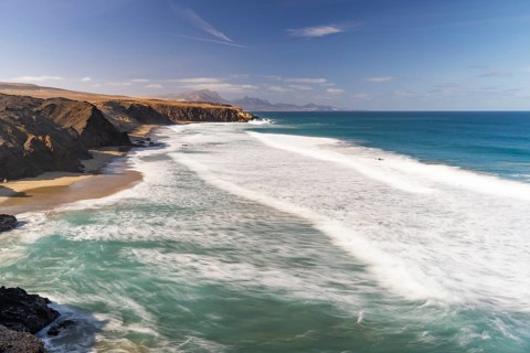 A stunning view of La Pared Beach in Fuerteventura with turquoise ocean waves crashing against the