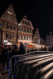 Crowd gathers at night in front of illuminated half-timbered houses and barriers, carnival, Calw,