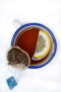 Black tea in cup with lemon slice and infusion bag