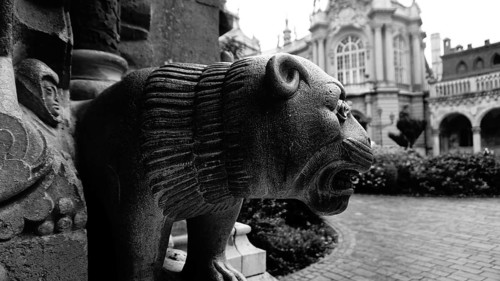 Close-up view of a lion sculpture in front of a historic building in black and white, Budapest