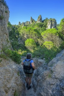 Woman with hiking backpack in the rock labyrinth of Mourèze, Département Hérault, France
