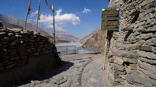 View of a rocky mountain road with a gate and sign to the entrance to the Upper Mustang region and