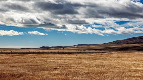 Large, wide fields under a sky with dramatic drifting clouds and hills, the endless expanse of the