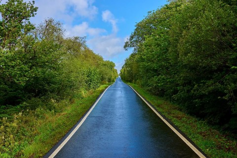 A long, straight road through a green landscape under a sunny blue sky, Tarbert, Loch Fyne,