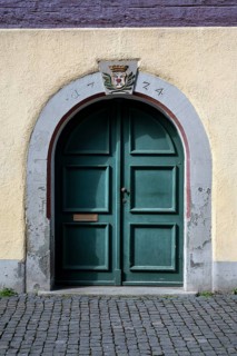 Green door under a round arch with coat of arms in the historic old town of Constance, traditional