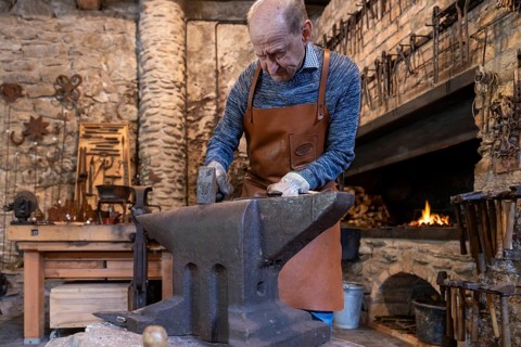 An elderly blacksmith works in his traditional workshop in the Salzburg region of Austria, keeping