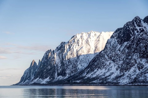 Spectacular view of snow-capped mountains reflecting in the clear blue waters of Ersfjord, Norway,