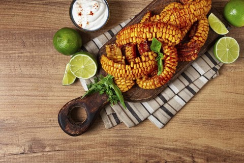 Corn ribs, with cream sauce, spices and lime, appetizer, on a wooden cutting board, homemade, no