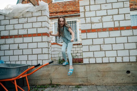 A young girl energetically plays and explores a construction site, demonstrating a sense of