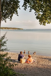 Couple sunbathing on the water, Herrsching am Lake Ammer, Bavaria, Germany