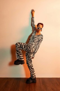 A stylish young woman poses confidently against the wall in a bold zebra print ensemble. She exudes
