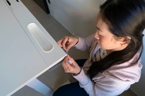 A young Asian woman is intricately involved in a DIY furniture project at home, skillfully