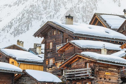 Snow-covered old farmhouses, large wooden cross, historic town center, Grimentz, Val d'Anniviers,