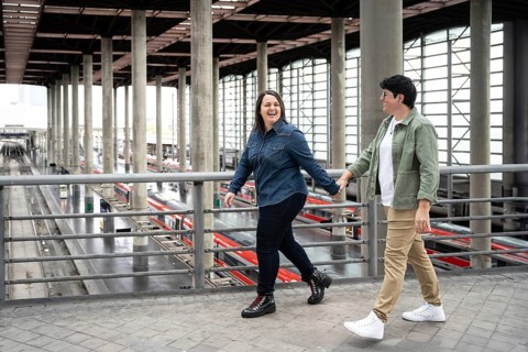 A joyful lesbian couple enjoys a day out, holding hands while walking through a modern train